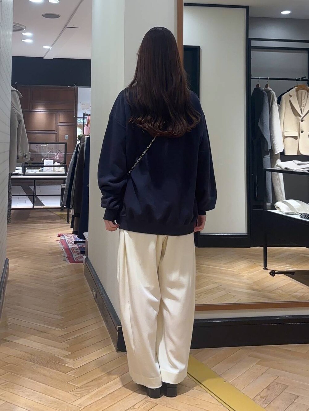 ホワイト系のスラックス、ブラック系のローファー、ブルー系のスウェットを着用したレディースの秋コーディネートの5枚目の写真