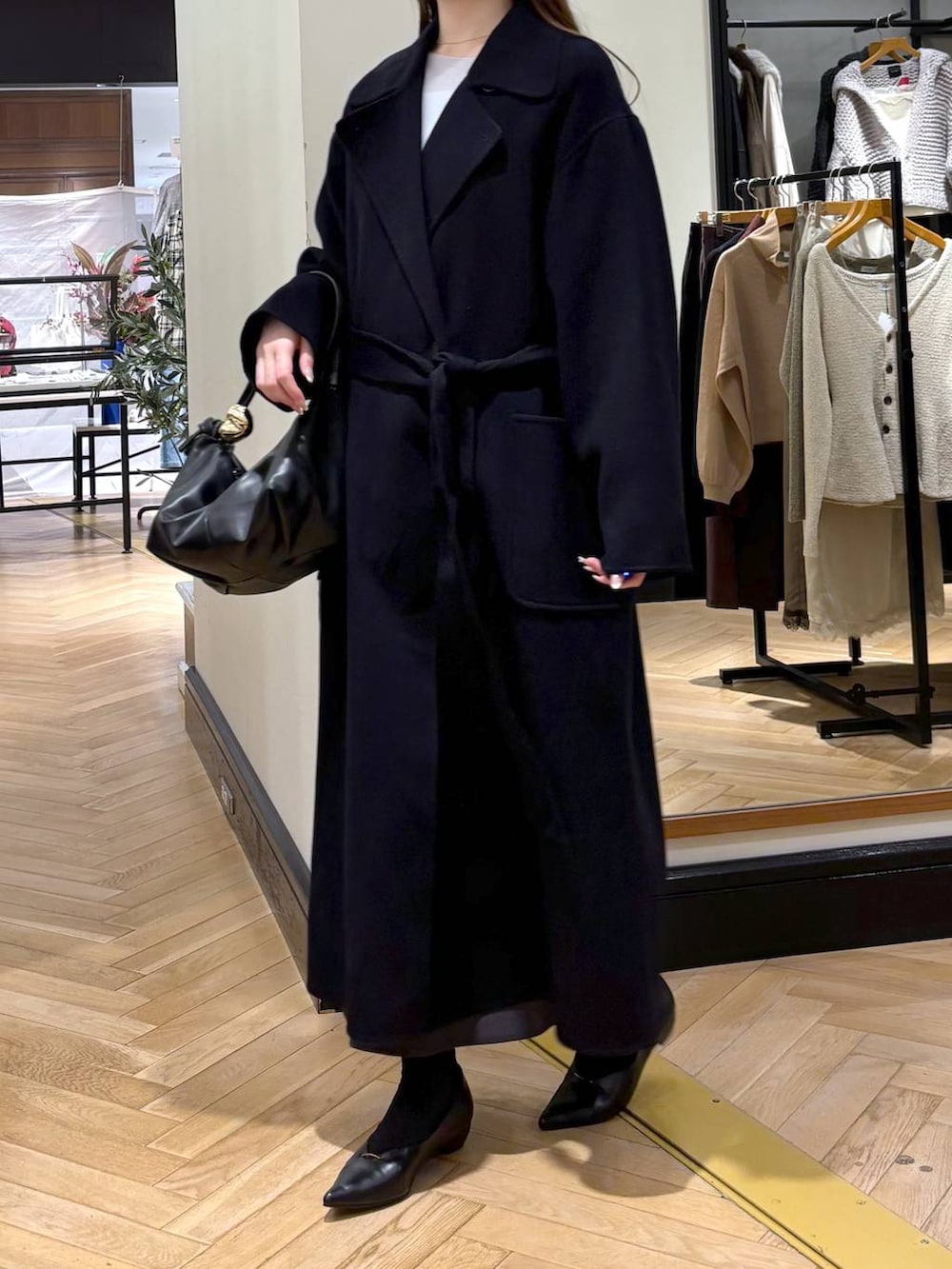 ブラック系のパンプス、ブルー系のステンカラーコート、ブラック系のショルダーバッグを着用したレディースの秋コーディネートの2枚目の写真