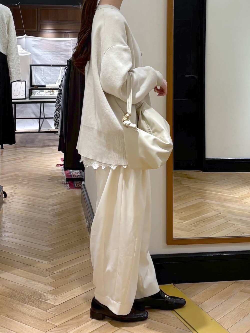 ホワイト系のスラックス、ブラック系のローファー、ホワイト系のカーディガン/ボレロを着用したレディースの冬コーディネートの2枚目の写真