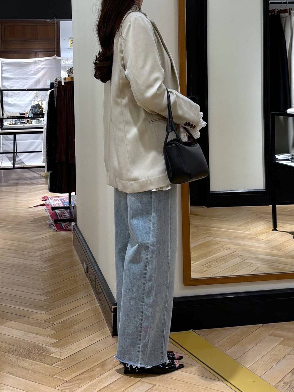 ブルー系のデニムパンツ、ベージュ系のノーカラージャケット、ブラック系のショルダーバッグを着用したレディースの春コーディネートの2枚目の写真