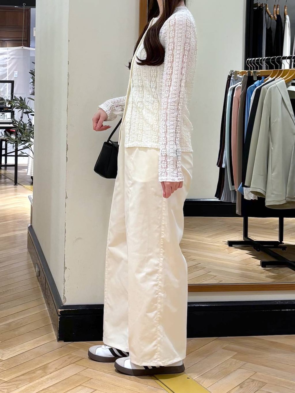 ホワイト系のスラックス、ブラック系のショルダーバッグ、ホワイト系のカーディガン/ボレロを着用したレディースの春コーディネートの4枚目の写真