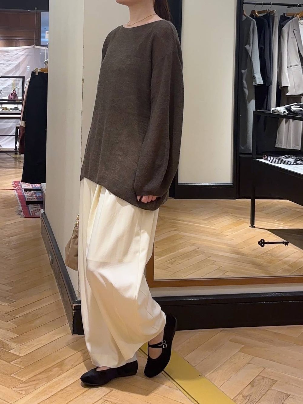 ブラウン系のニット/セーター、ホワイト系のスラックス、ベージュ系のショルダーバッグを着用したレディースの秋コーディネートの3枚目の写真