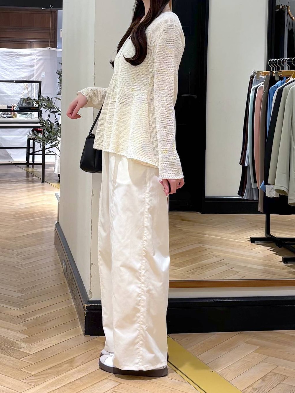 ホワイト系のスラックス、ブラック系のショルダーバッグ、ホワイト系のカーディガン/ボレロを着用したレディースの春コーディネートの3枚目の写真