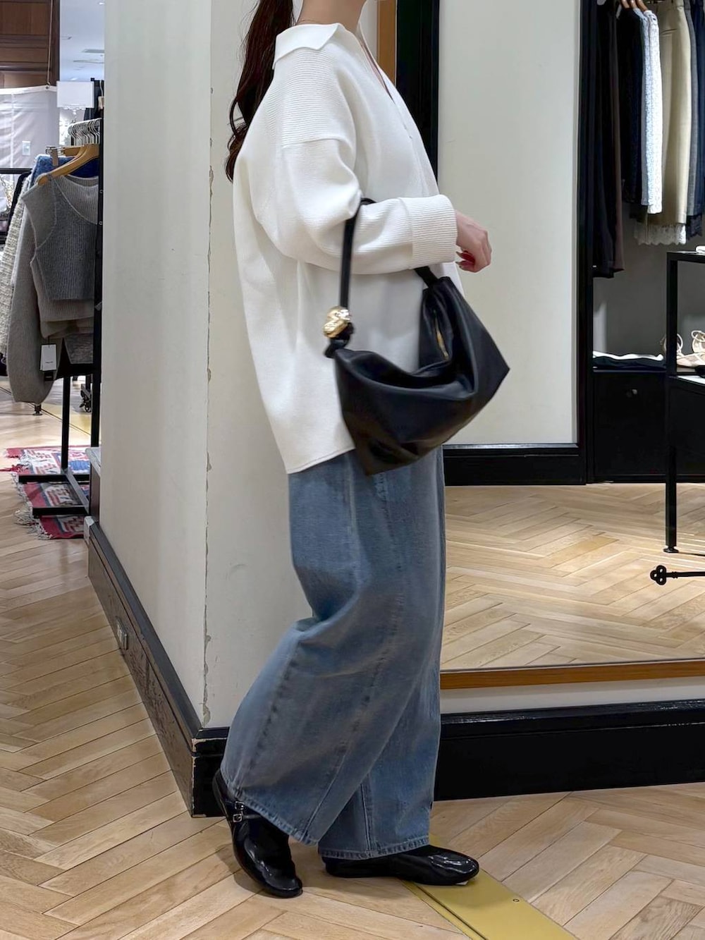 ブルー系のデニムパンツ、ブラック系のショルダーバッグ、ホワイト系のニット/セーターを着用したレディースの冬コーディネートの2枚目の写真