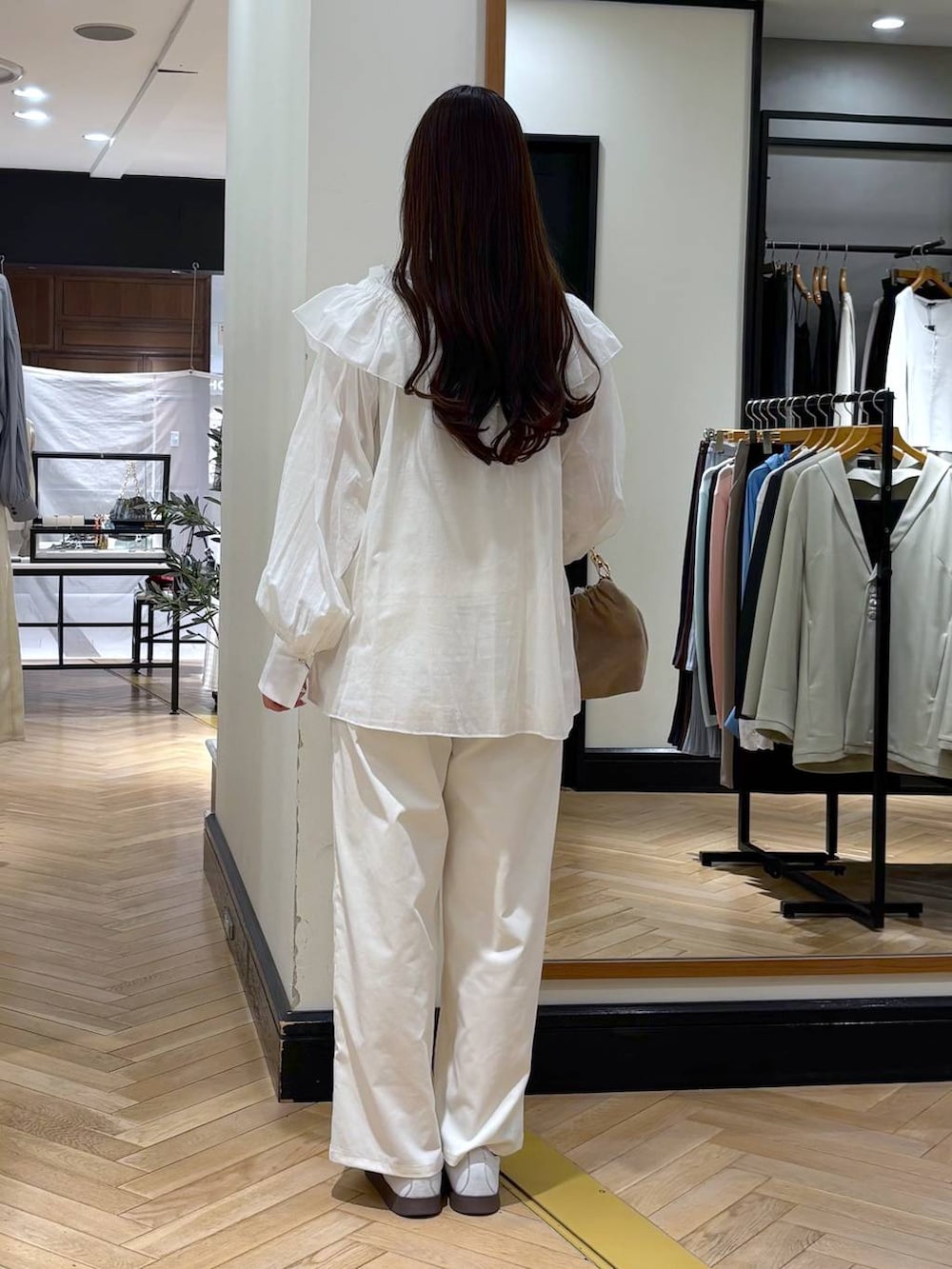 ベージュ系のショルダーバッグ、ホワイト系のTシャツ/カットソー、ホワイト系のスラックスを着用したレディースの春コーディネートの4枚目の写真