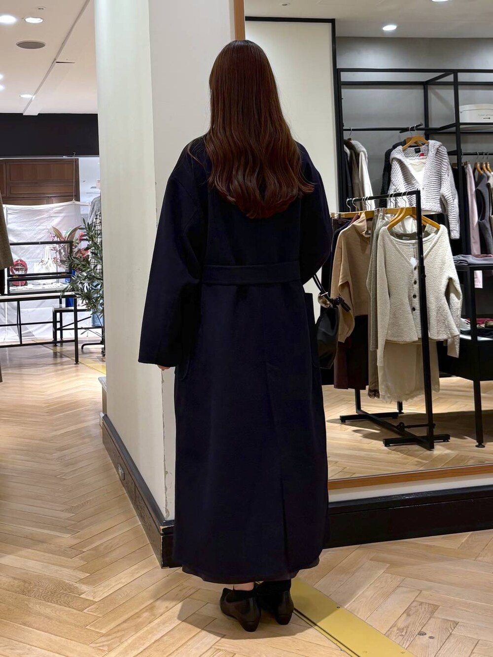 ブラック系のパンプス、ブルー系のステンカラーコート、ブラック系のショルダーバッグを着用したレディースの秋コーディネートの4枚目の写真