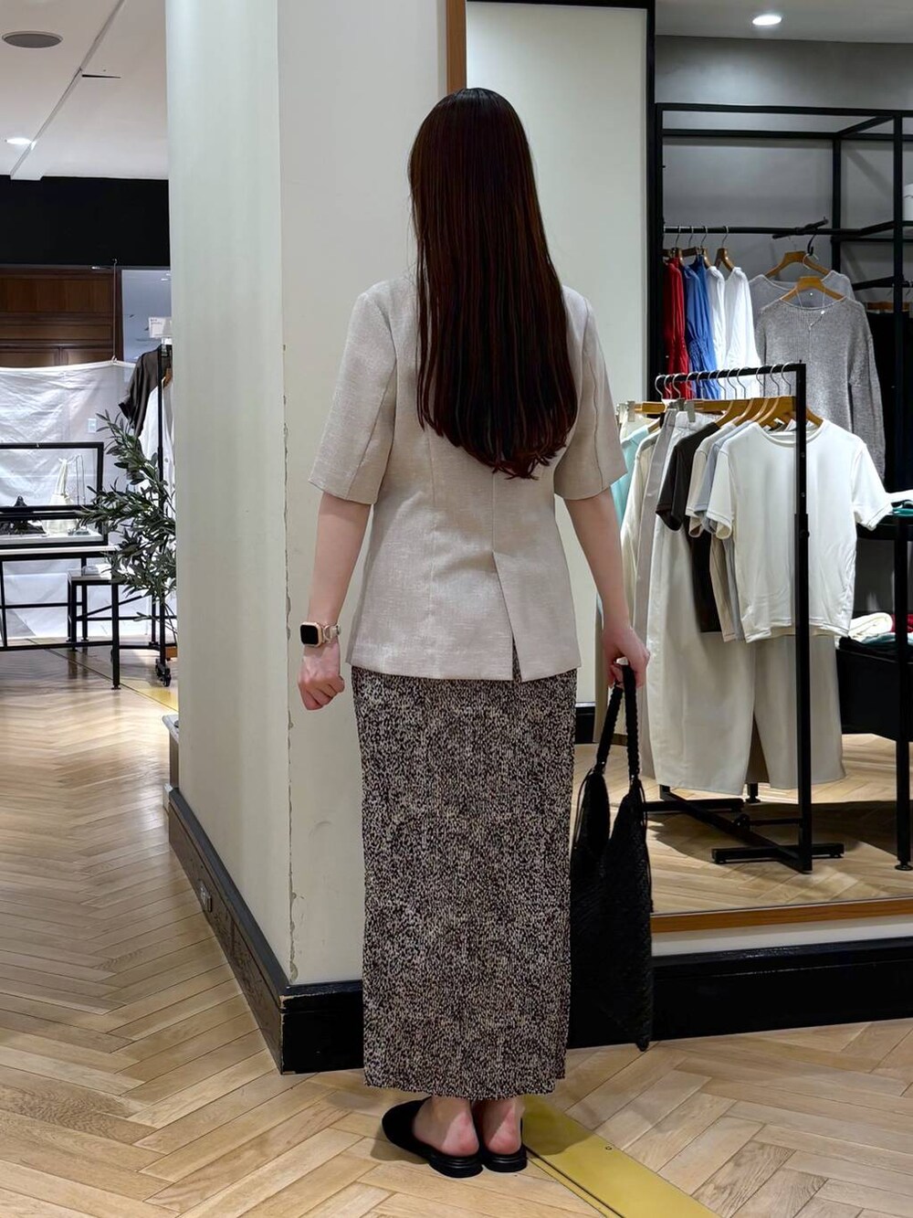 ベージュ系のスカート、ベージュ系のノーカラージャケット、ブラック系のサンダルを着用したレディースの春コーディネートの4枚目の写真