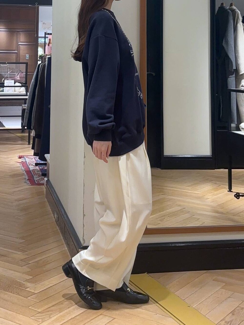 ホワイト系のスラックス、ブラック系のローファー、ブルー系のスウェットを着用したレディースの秋コーディネートの3枚目の写真