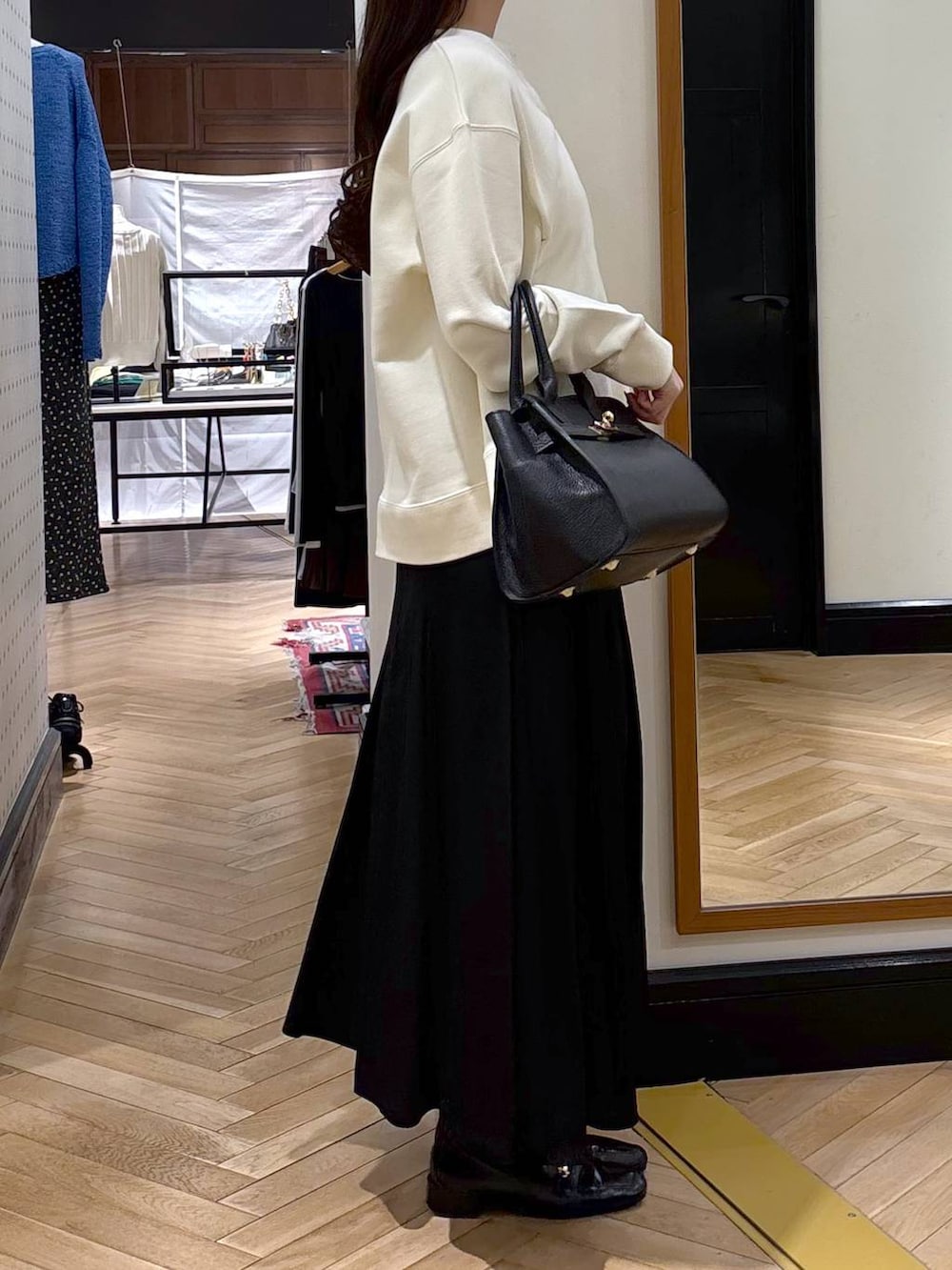 ブラック系のローファー、ブラック系のショルダーバッグ、ブラック系のスカートを着用したレディースの春コーディネートの2枚目の写真