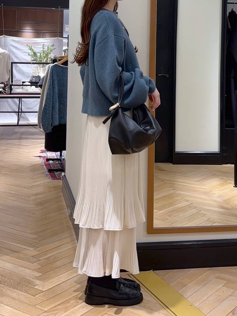 ホワイト系のスカート、ブルー系のカーディガン/ボレロ、ブラック系のショルダーバッグを着用したレディースの冬コーディネートの2枚目の写真