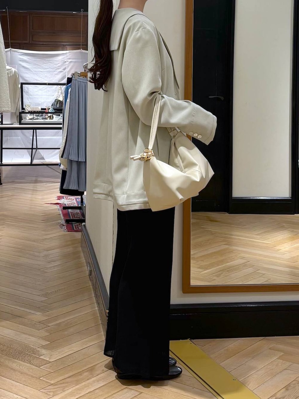 ブラック系のスカート、ベージュ系のショルダーバッグ、ベージュ系のテーラードジャケットを着用したレディースの春コーディネートの2枚目の写真