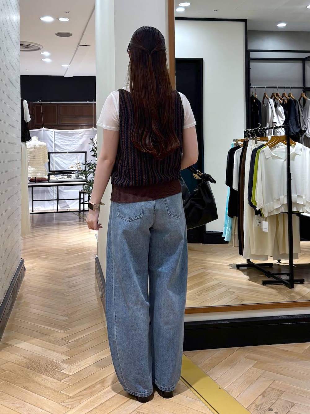 ブラック系のショルダーバッグ、ブルー系のデニムパンツ、ブラック系のパンプスを着用したレディースの夏コーディネートの4枚目の写真