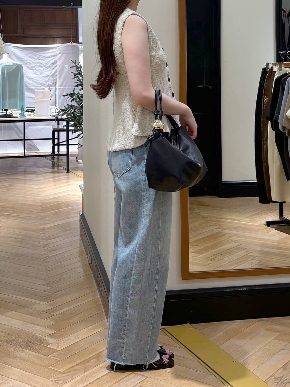 ホワイト系のベスト、ブラック系のショルダーバッグ、ブルー系のデニムパンツを着用したレディースの夏コーディネートの3枚目の写真