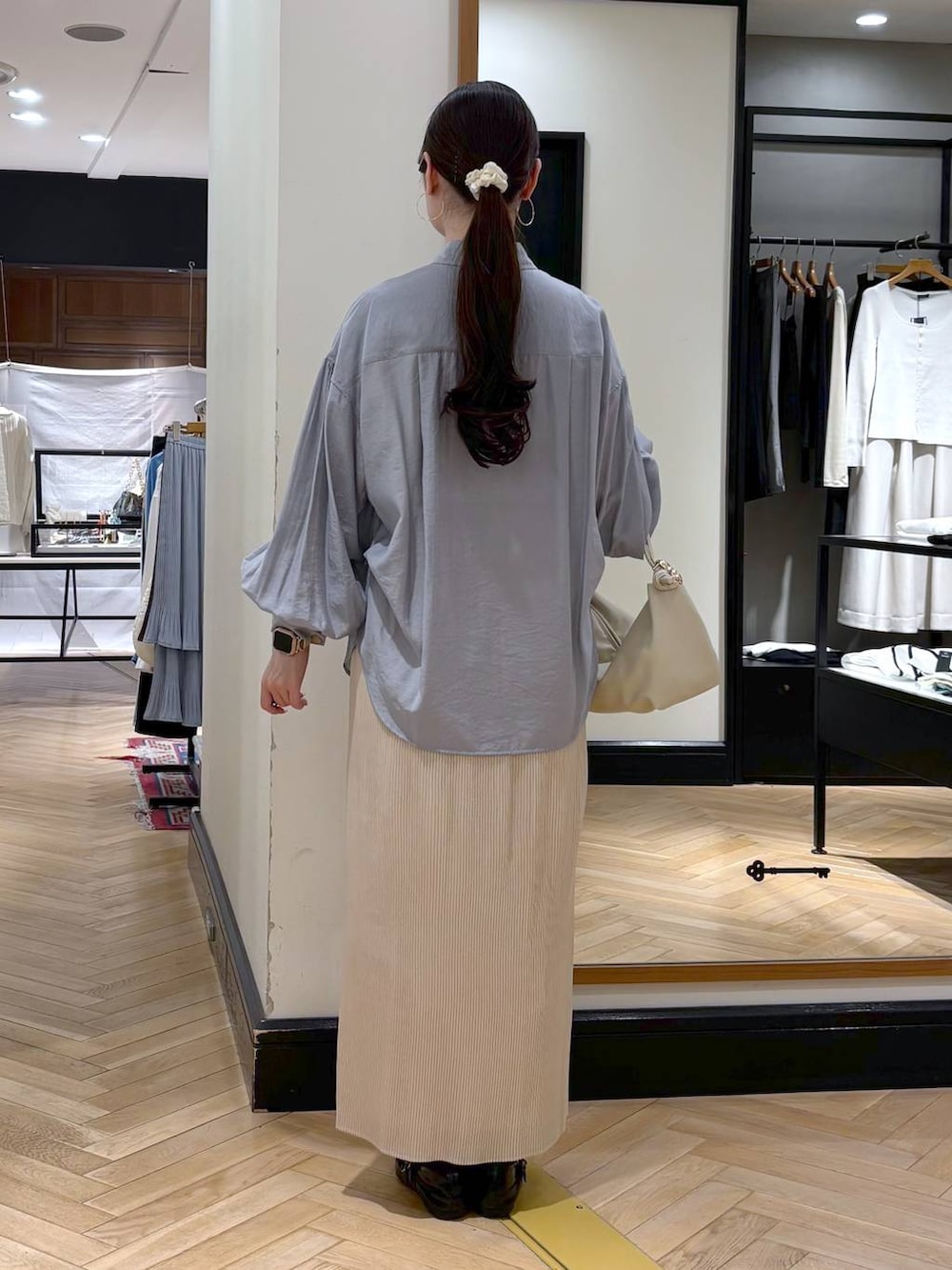 ホワイト系のスカート、ベージュ系のショルダーバッグ、ブルー系のシャツ/ブラウスを着用したレディースの春コーディネートの4枚目の写真