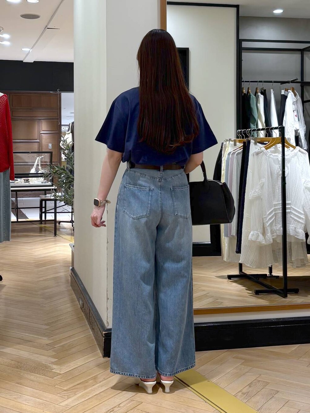 ブラック系のショルダーバッグ、ブルー系のデニムパンツ、ホワイト系のサンダルを着用したレディースの春コーディネートの4枚目の写真
