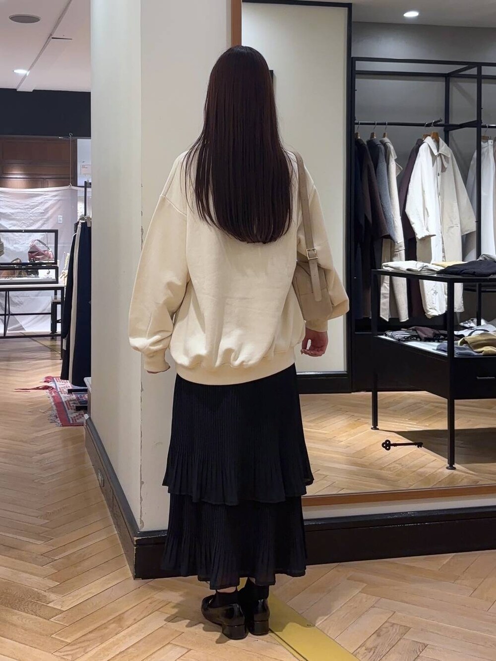 ブラック系のスカート、ブラック系のローファー、ホワイト系のスウェットを着用したレディースの秋コーディネートの3枚目の写真