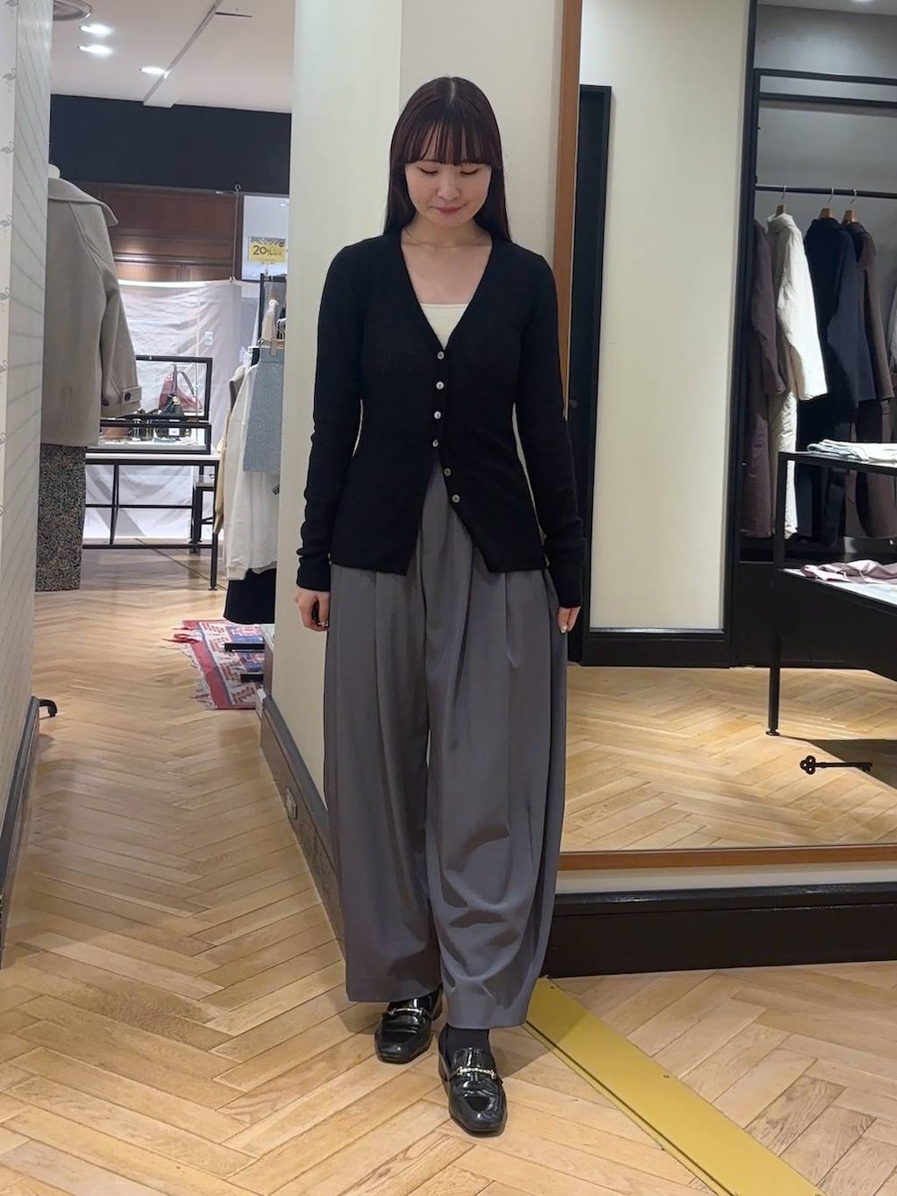 グレー系のスラックス、ブラック系のローファー、ブラック系のボストンバッグを着用したレディースの秋コーディネートの2枚目の写真