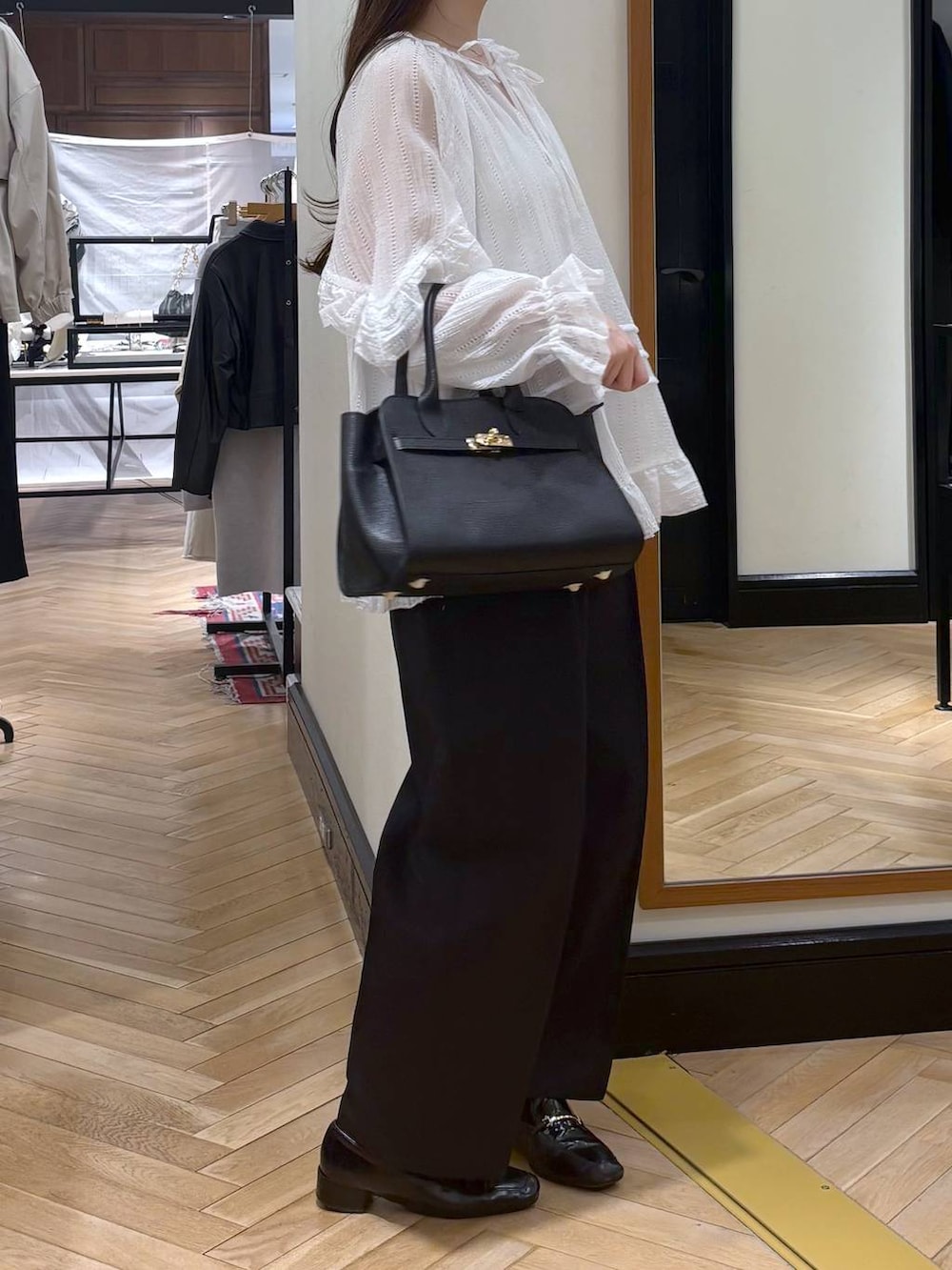 ブラック系のローファー、ブラック系のショルダーバッグ、ホワイト系のシャツ/ブラウスを着用したレディースの春コーディネートの2枚目の写真