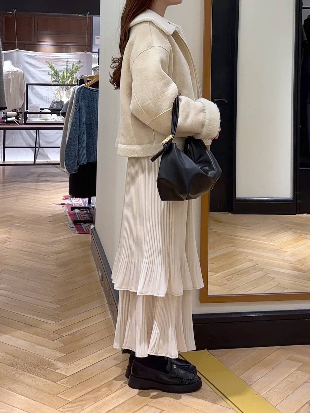 ホワイト系のスカート、ブルー系のカーディガン/ボレロ、ブラック系のショルダーバッグを着用したレディースの冬コーディネートの2枚目の写真