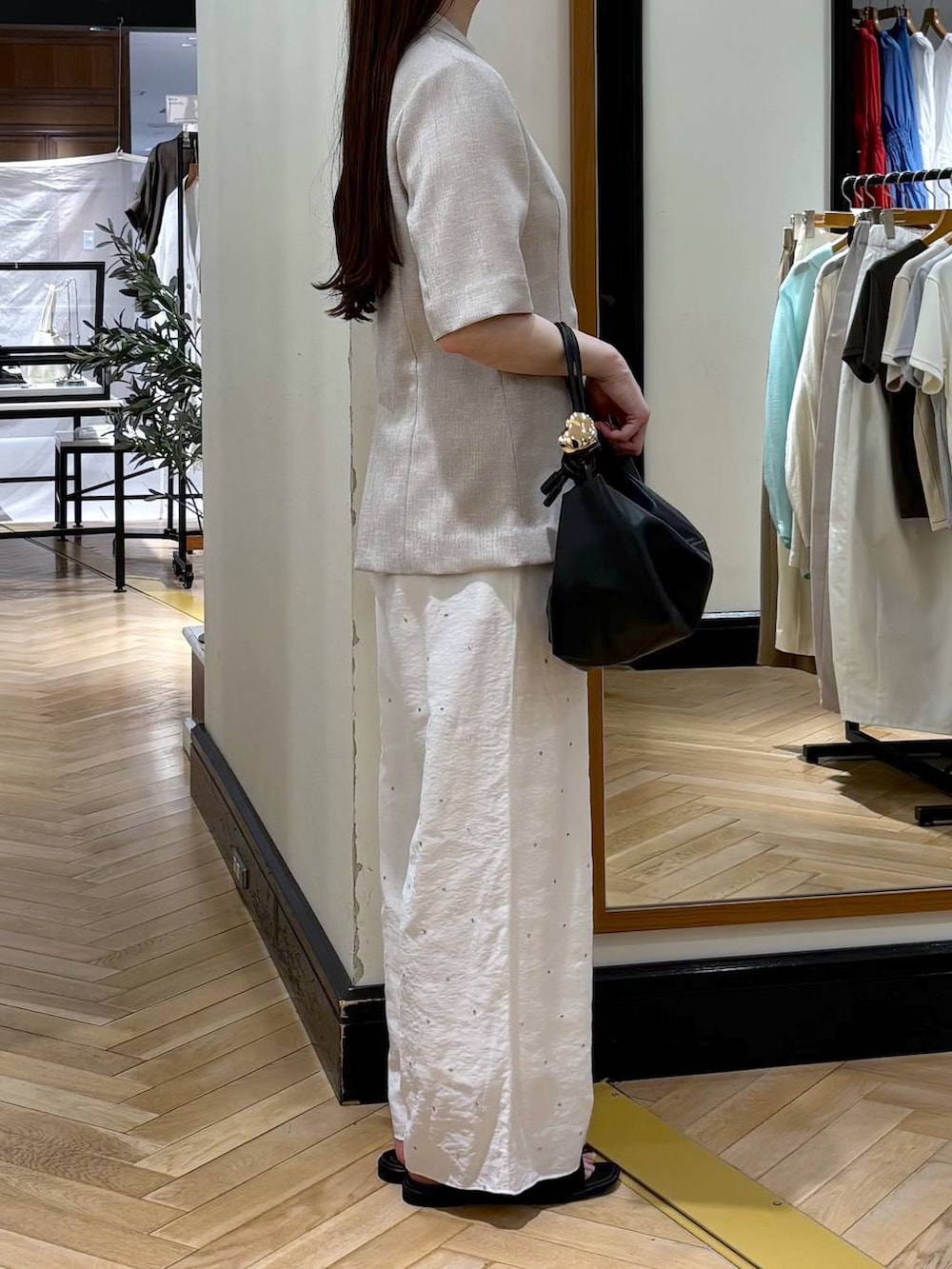 ブラック系のショルダーバッグ、ベージュ系のノーカラージャケット、ホワイト系のその他パンツを着用したレディースの春コーディネートの2枚目の写真