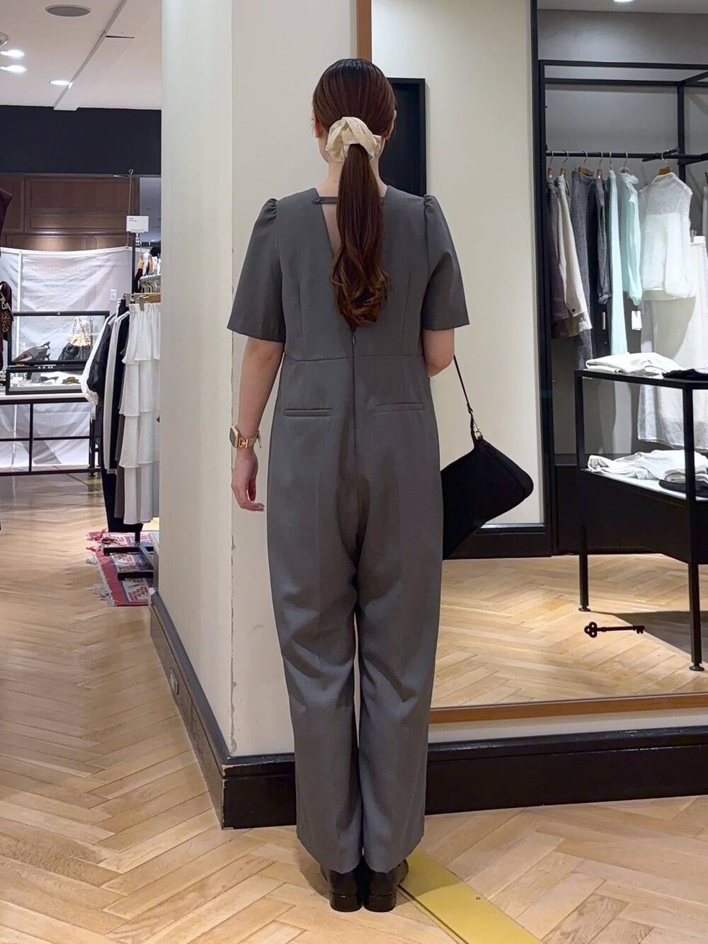 ブラック系のパンプス、ブラック系のショルダーバッグ、グレー系のつなぎ/オールインワンを着用したレディースの秋コーディネートの6枚目の写真