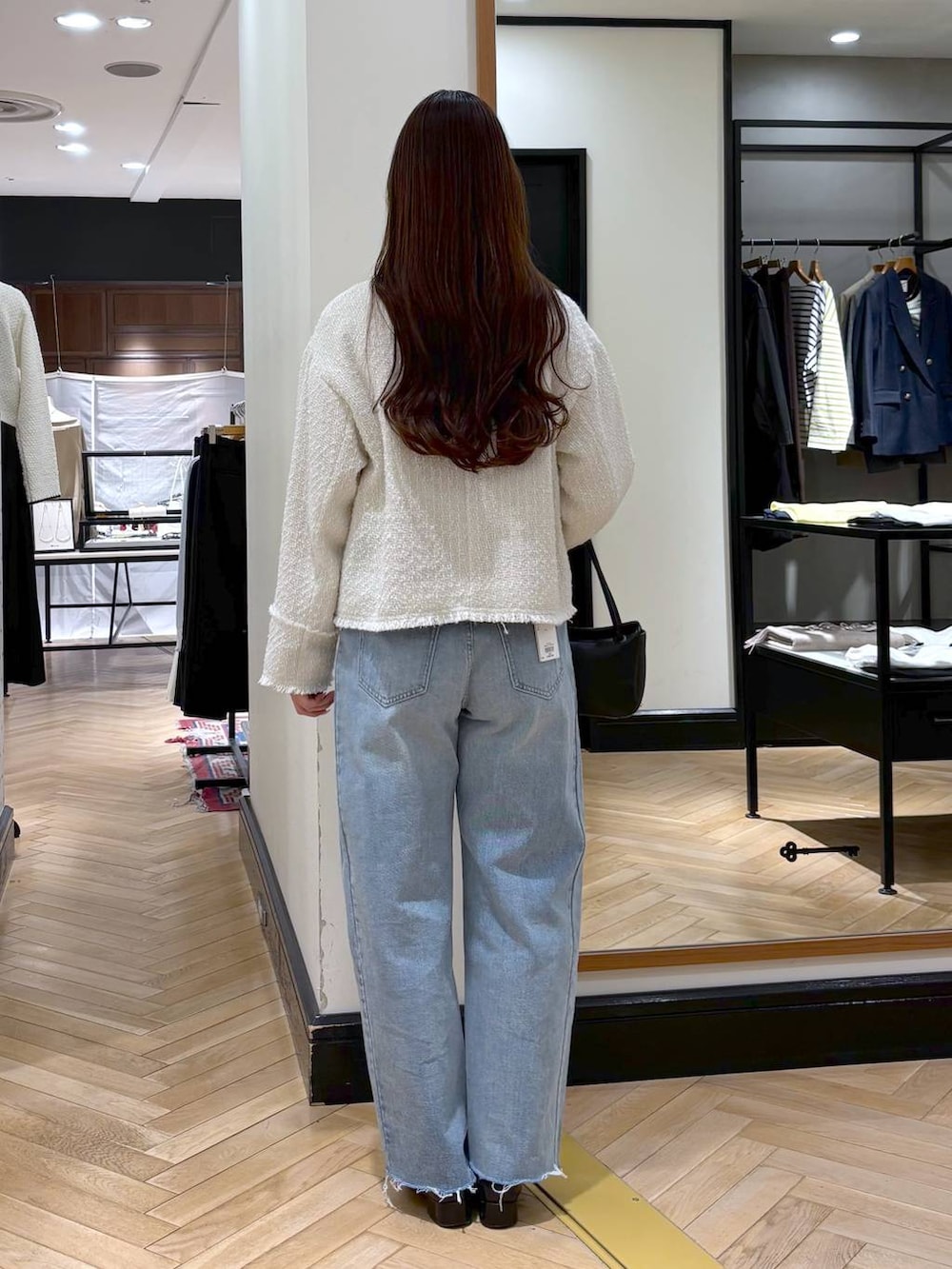 ブラック系のローファー、ブルー系のデニムパンツ、ホワイト系のノーカラージャケットを着用したレディースの冬コーディネートの4枚目の写真