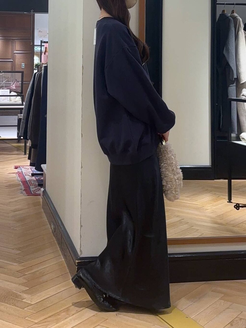 ブラック系のローファー、ブルー系のスカート、ベージュ系のハンドバッグを着用したレディースの秋コーディネートの2枚目の写真