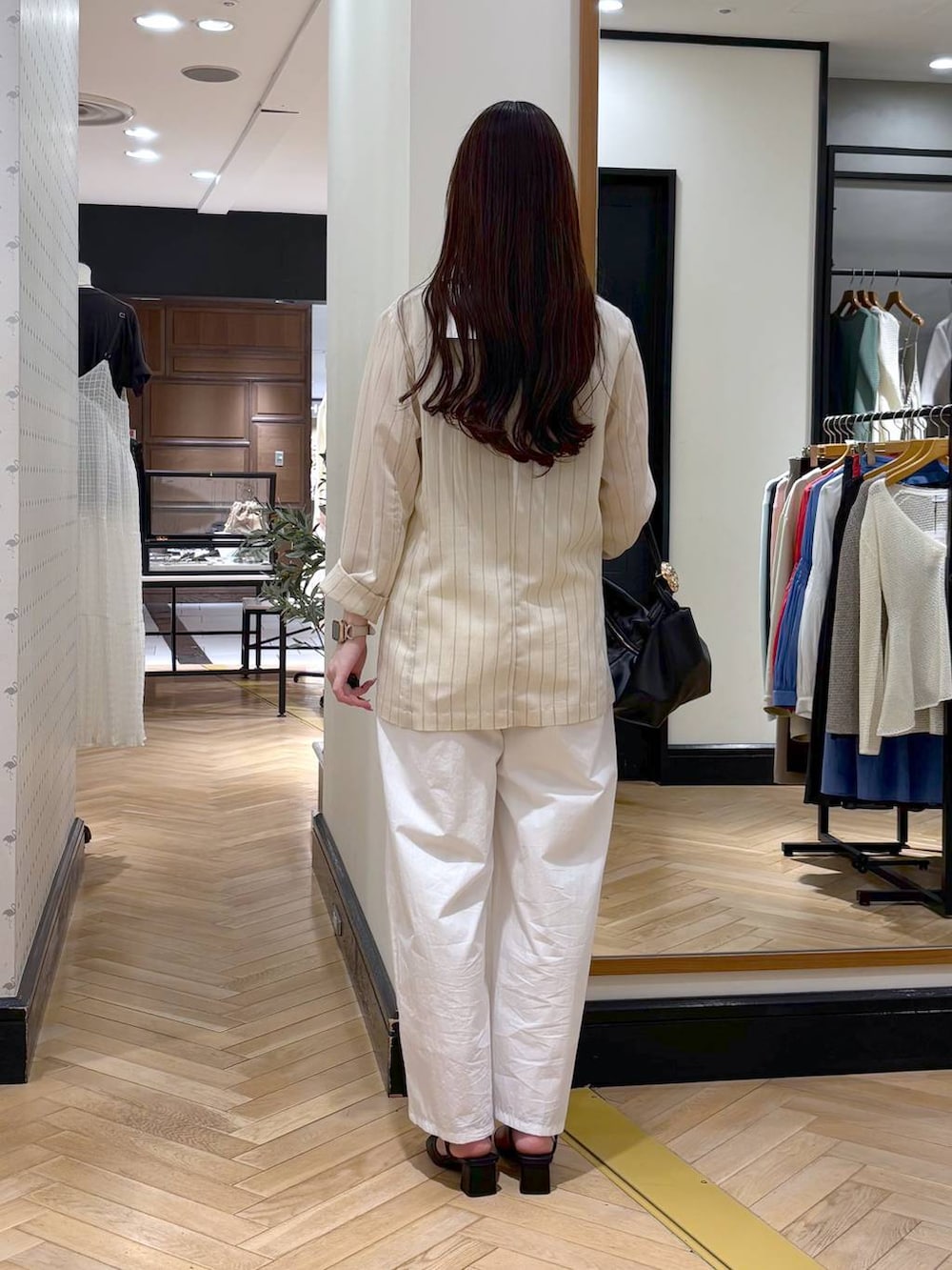 ベージュ系のテーラードジャケット、ブラック系のショルダーバッグ、ホワイト系のタンクトップを着用したレディースの春コーディネートの4枚目の写真