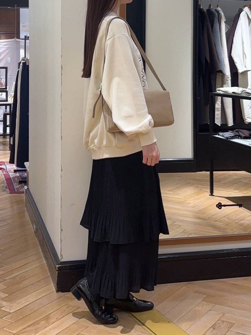 ブラック系のスカート、ブラック系のローファー、ホワイト系のスウェットを着用したレディースの秋コーディネートの2枚目の写真