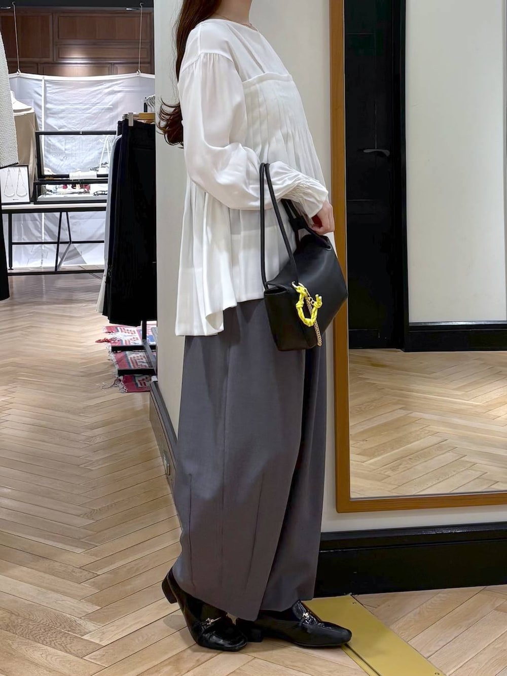 グレー系のスラックス、ブラック系のローファー、ブラック系のショルダーバッグを着用したレディースの冬コーディネートの2枚目の写真