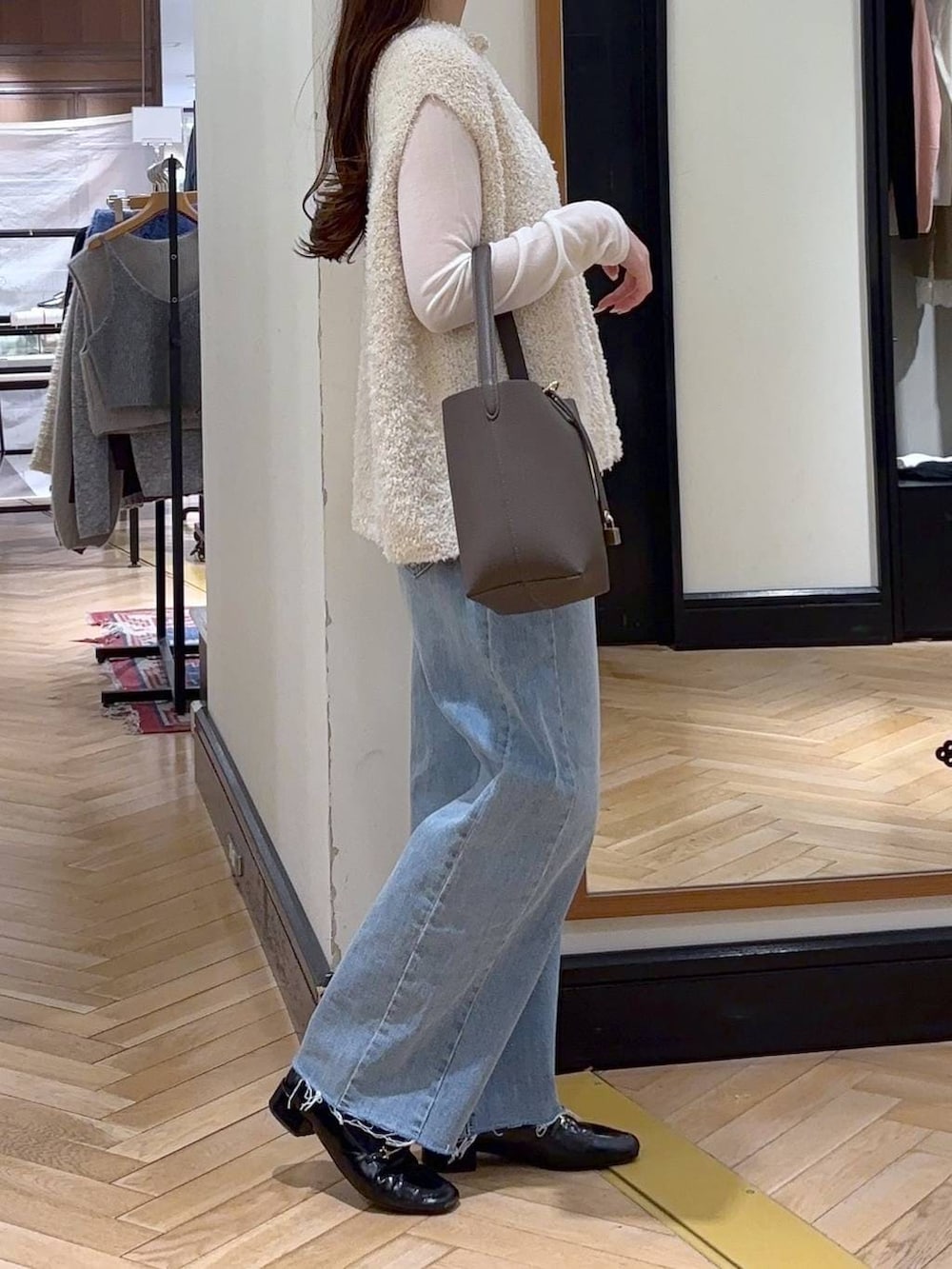 ブラック系のローファー、ブルー系のデニムパンツ、ホワイト系のベストを着用したレディースの冬コーディネートの2枚目の写真