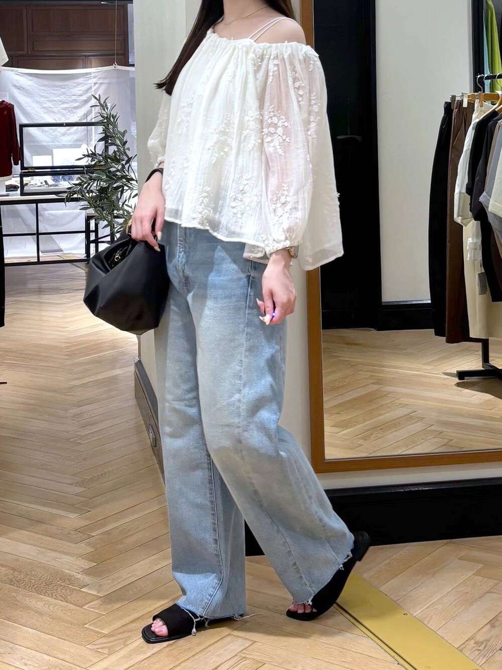 ホワイト系のシャツ/ブラウス、ブラック系のショルダーバッグ、ブルー系のデニムパンツを着用したレディースの夏コーディネートの3枚目の写真