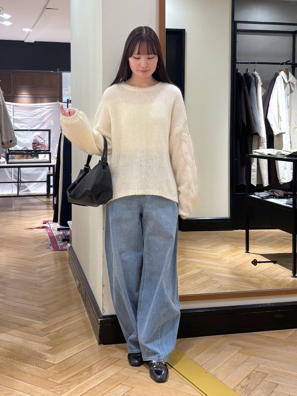 ブルー系のデニムパンツ、ブラック系のローファー、ホワイト系のニット/セーターを着用したレディースの秋コーディネートの2枚目の写真