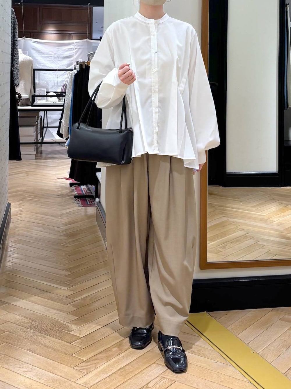 ベージュ系のスラックス、ブラック系のローファー、ホワイト系のTシャツ/カットソーを着用したレディースの冬コーディネートの2枚目の写真