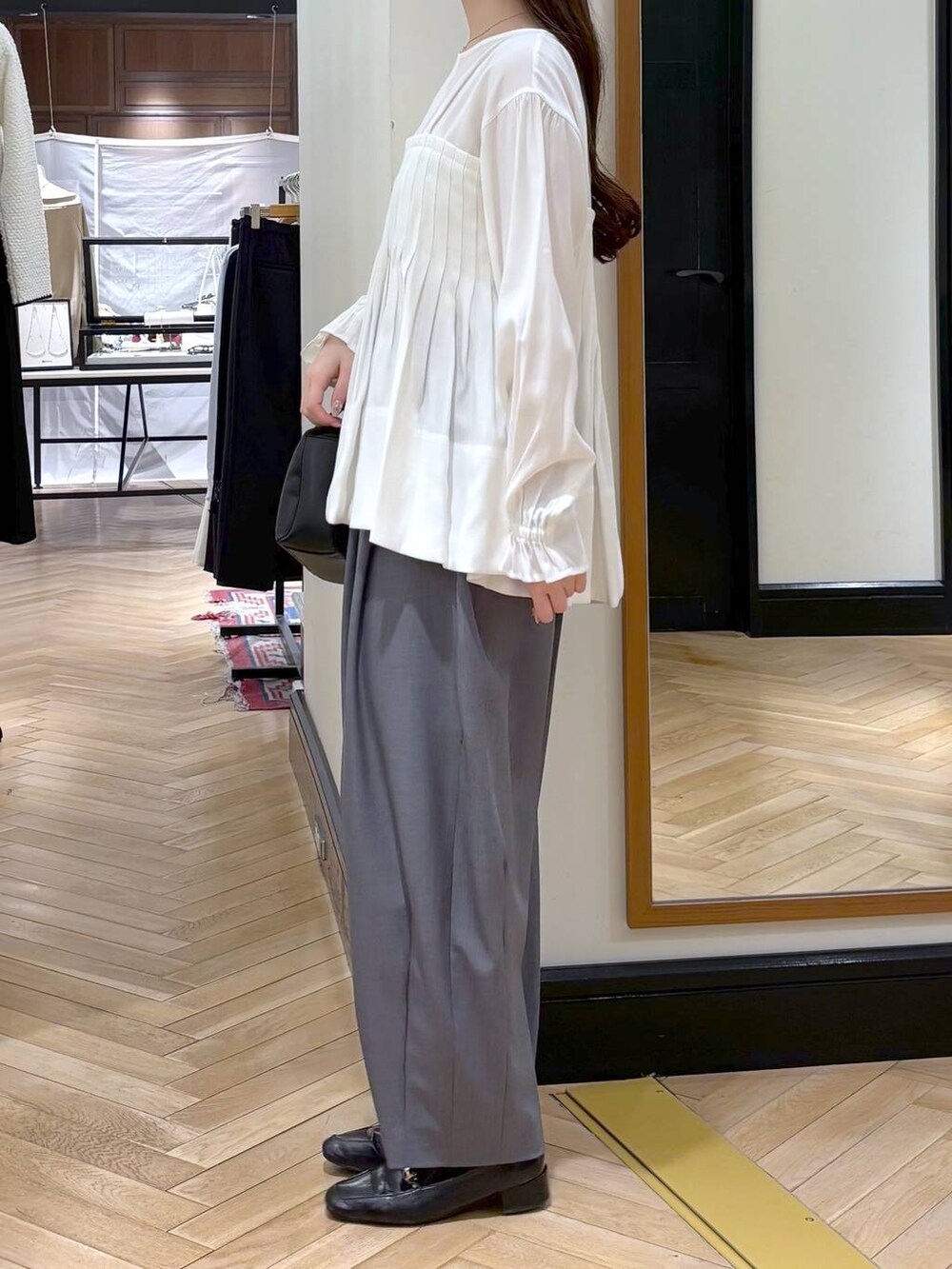 グレー系のスラックス、ブラック系のローファー、ブラック系のショルダーバッグを着用したレディースの冬コーディネートの4枚目の写真