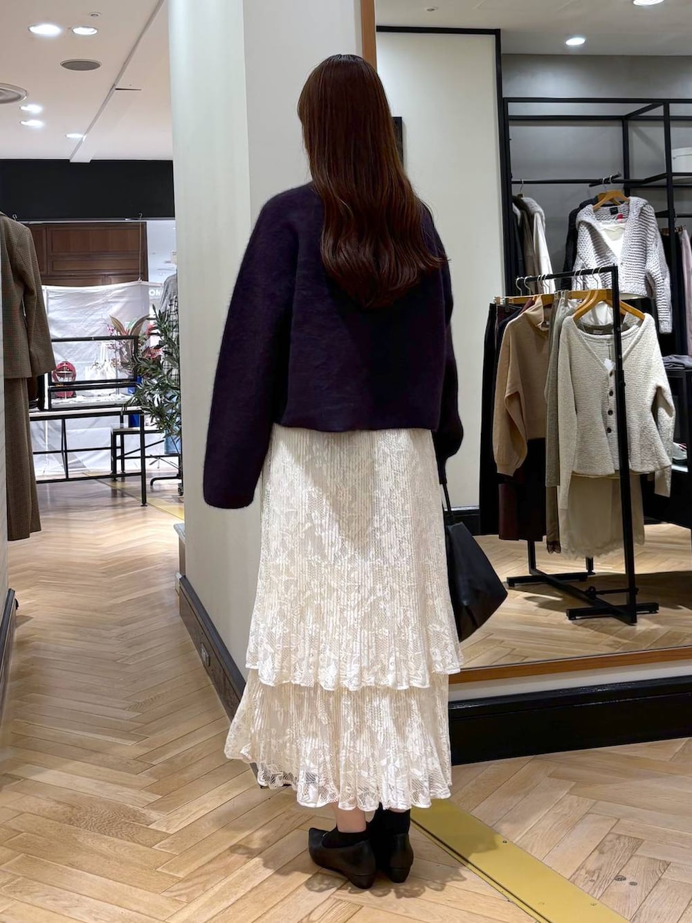 ブラック系のパンプス、ホワイト系のスカート、ブラック系のショルダーバッグを着用したレディースの秋コーディネートの4枚目の写真