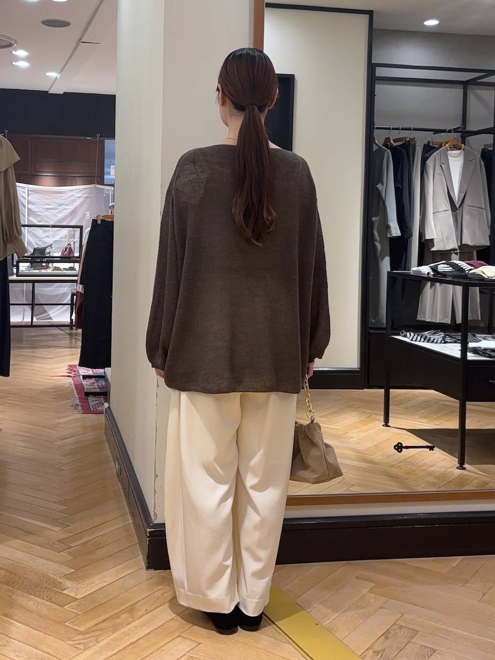 ブラウン系のニット/セーター、ホワイト系のスラックス、ベージュ系のショルダーバッグを着用したレディースの秋コーディネートの4枚目の写真