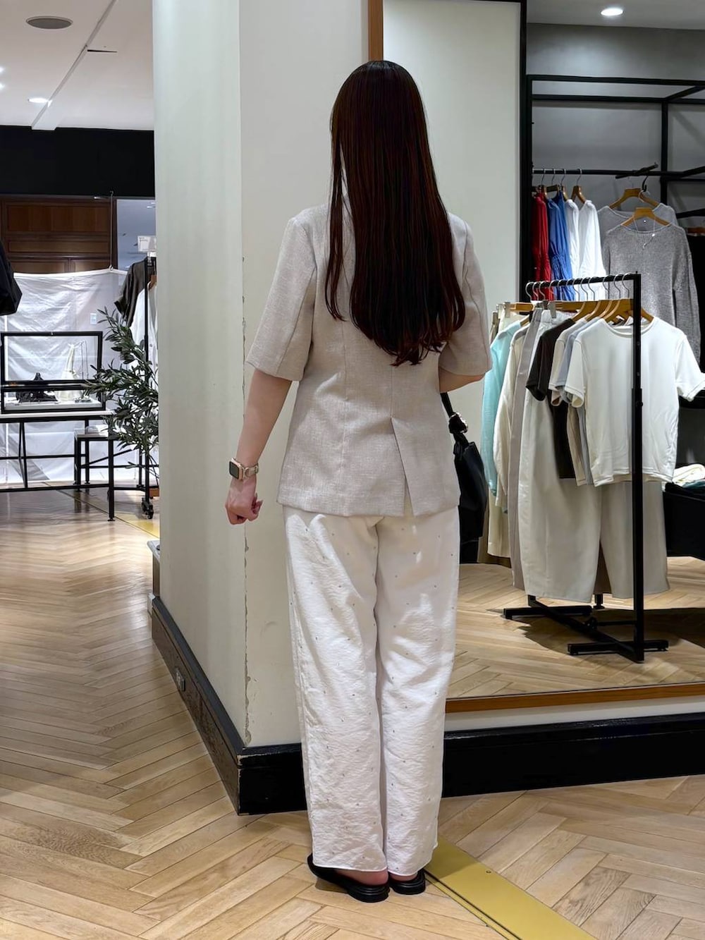 ブラック系のショルダーバッグ、ベージュ系のノーカラージャケット、ホワイト系のその他パンツを着用したレディースの春コーディネートの4枚目の写真