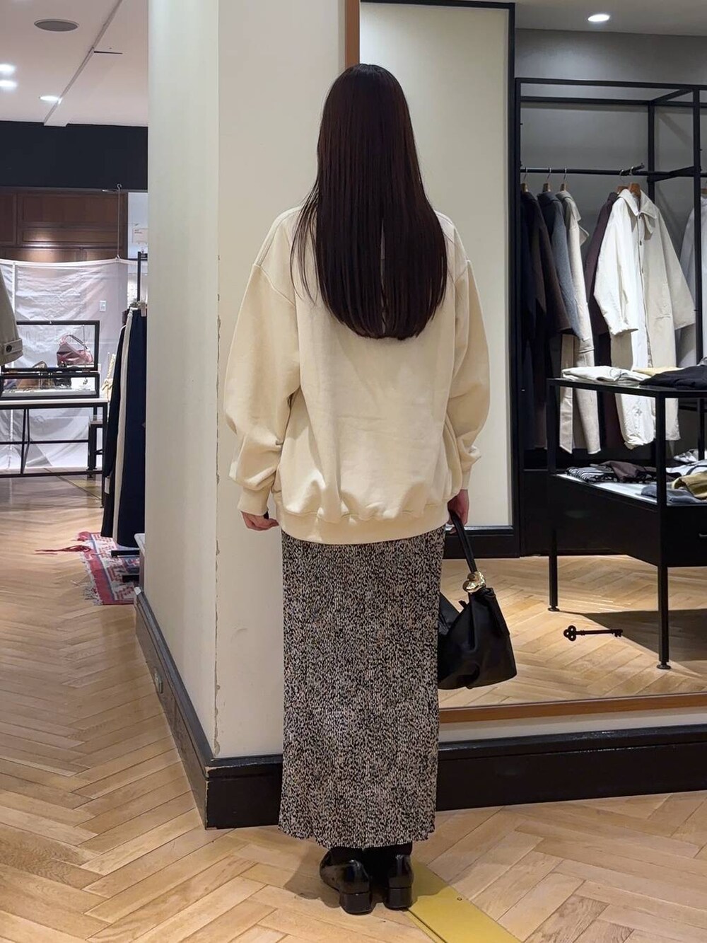 ブラック系のローファー、ベージュ系のスカート、ブラック系のショルダーバッグを着用したレディースの秋コーディネートの4枚目の写真