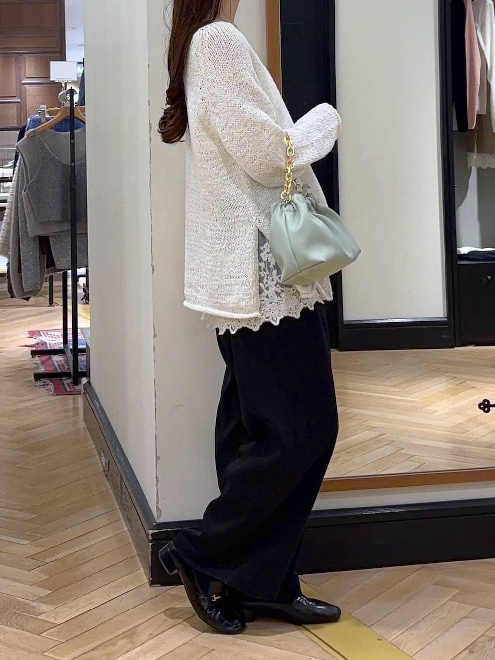 ブラック系のローファー、ブラック系のスラックス、グリーン系のショルダーバッグを着用したレディースの冬コーディネートの3枚目の写真