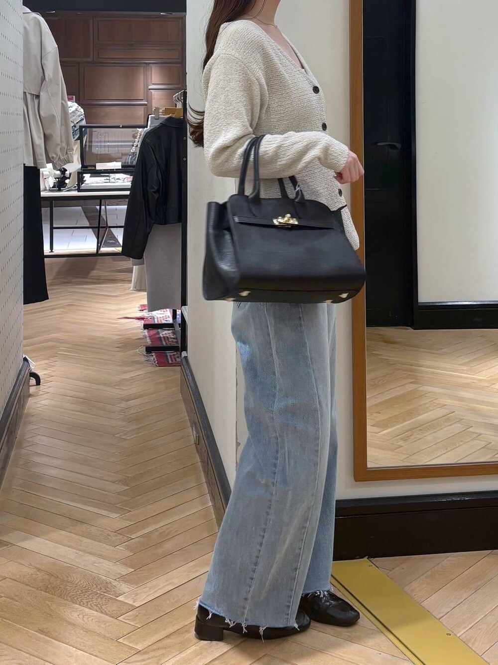 ブラック系のローファー、ブルー系のデニムパンツ、ブラック系のショルダーバッグを着用したレディースの春コーディネートの2枚目の写真