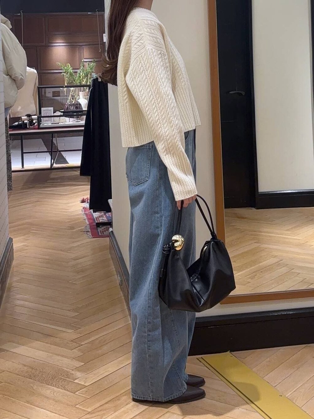 ブルー系のデニムパンツ、ブラウン系のブーツ、ブラック系のショルダーバッグを着用したレディースの冬コーディネートの2枚目の写真