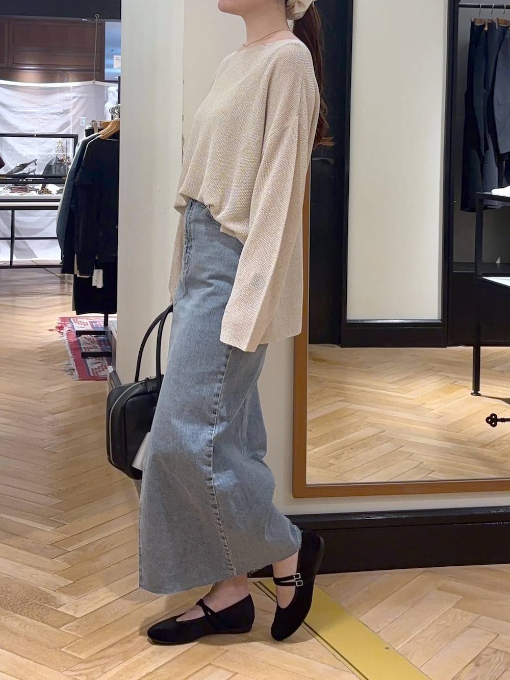 ブラック系のボストンバッグ、ブルー系のデニムスカート、ブラック系のバレエシューズを着用したレディースの秋コーディネートの3枚目の写真