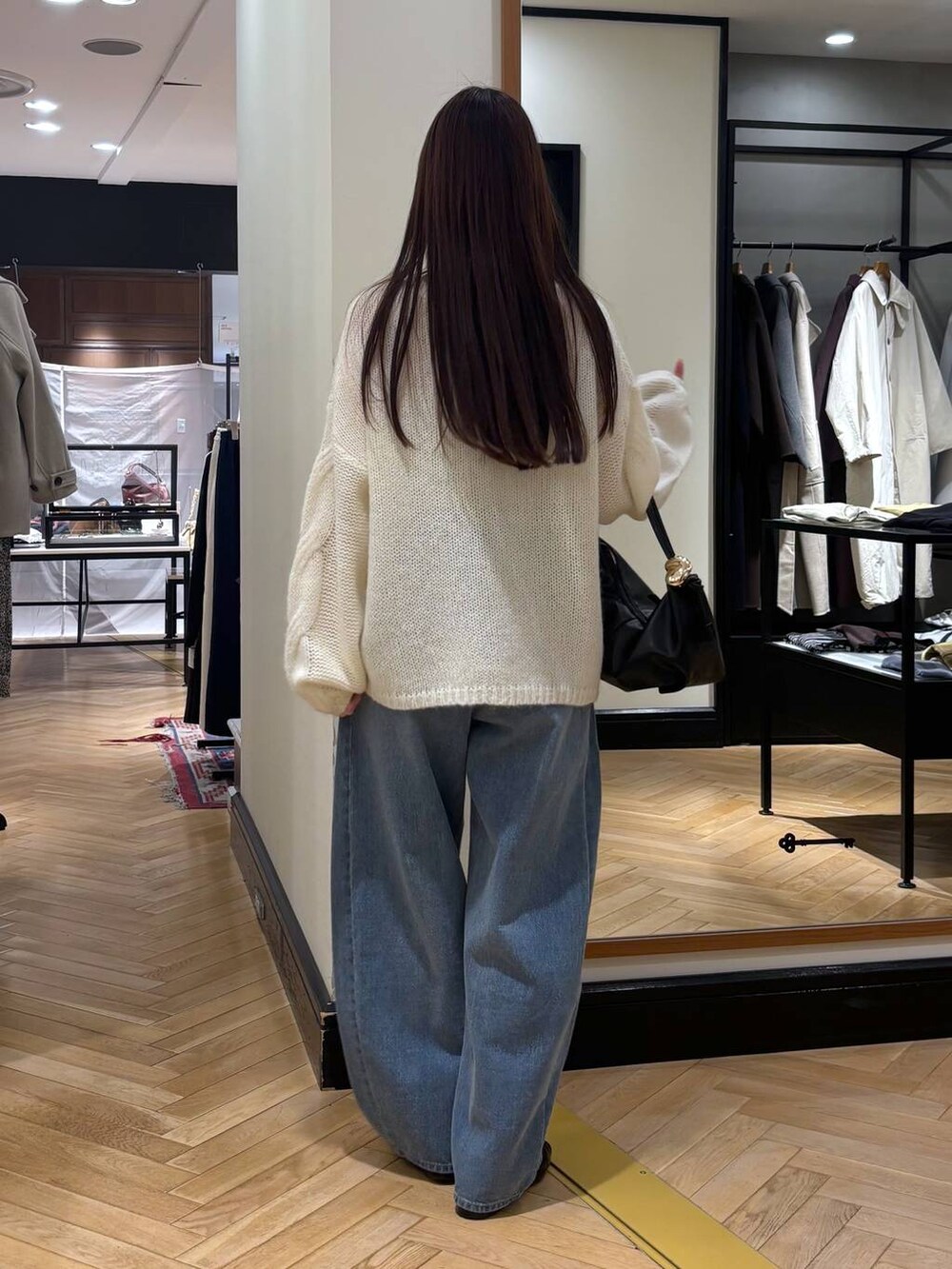 ブルー系のデニムパンツ、ブラック系のローファー、ホワイト系のニット/セーターを着用したレディースの秋コーディネートの5枚目の写真