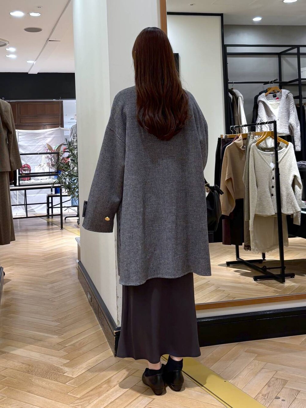 グレー系のスカート、ブラック系のパンプス、その他のノーカラーコートを着用したレディースの秋コーディネートの4枚目の写真