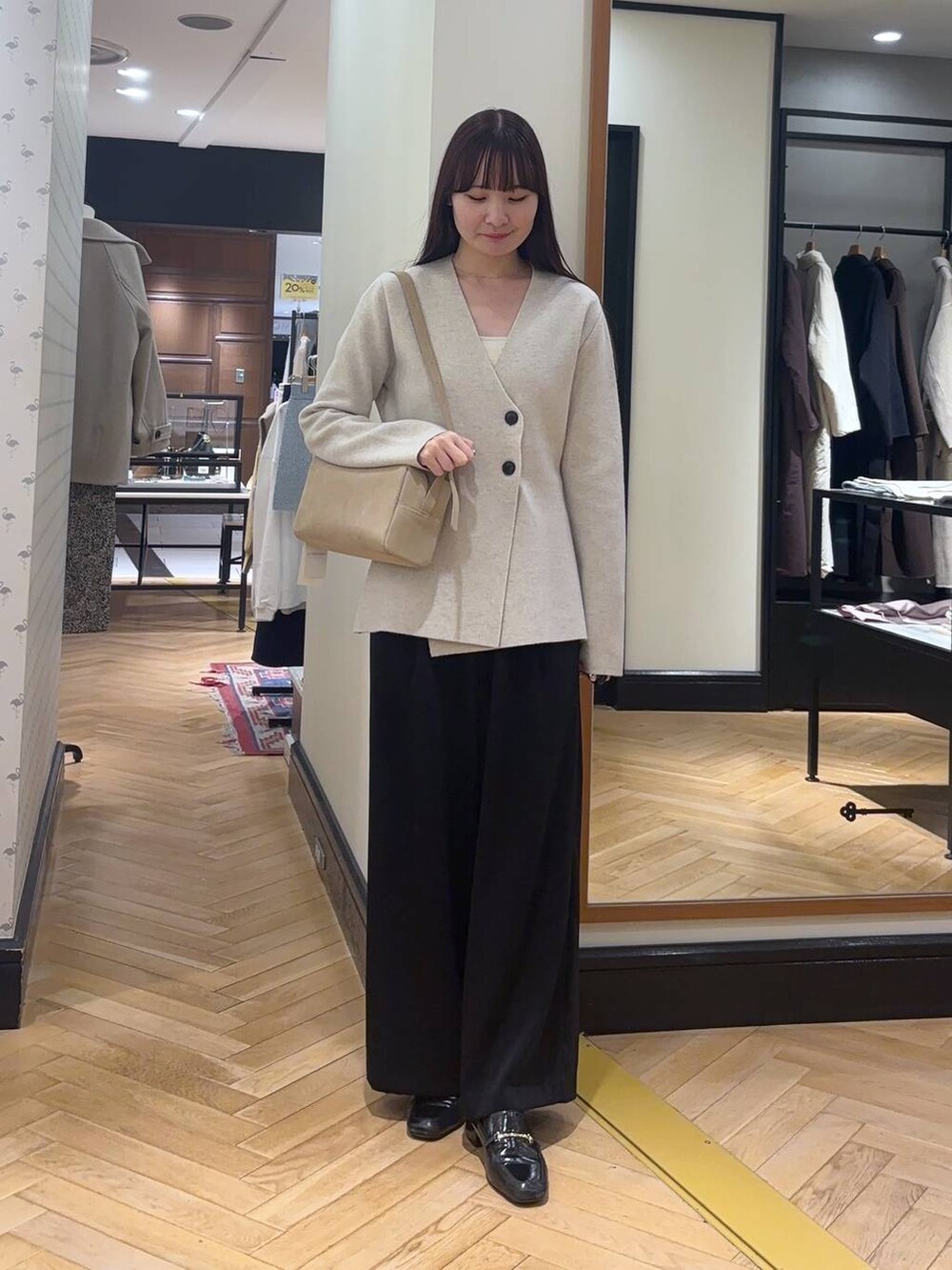 ブラック系のローファー、ブラック系のスラックス、ホワイト系のノーカラージャケットを着用したレディースの秋コーディネートの2枚目の写真