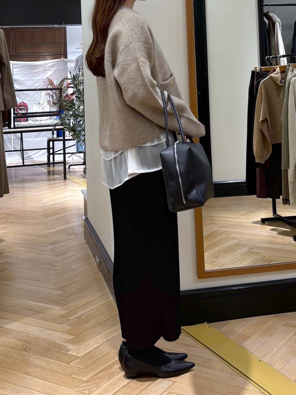 ブラック系のパンプス、ベージュ系のTシャツ/カットソー、ブラック系のスカートを着用したレディースの秋コーディネートの2枚目の写真