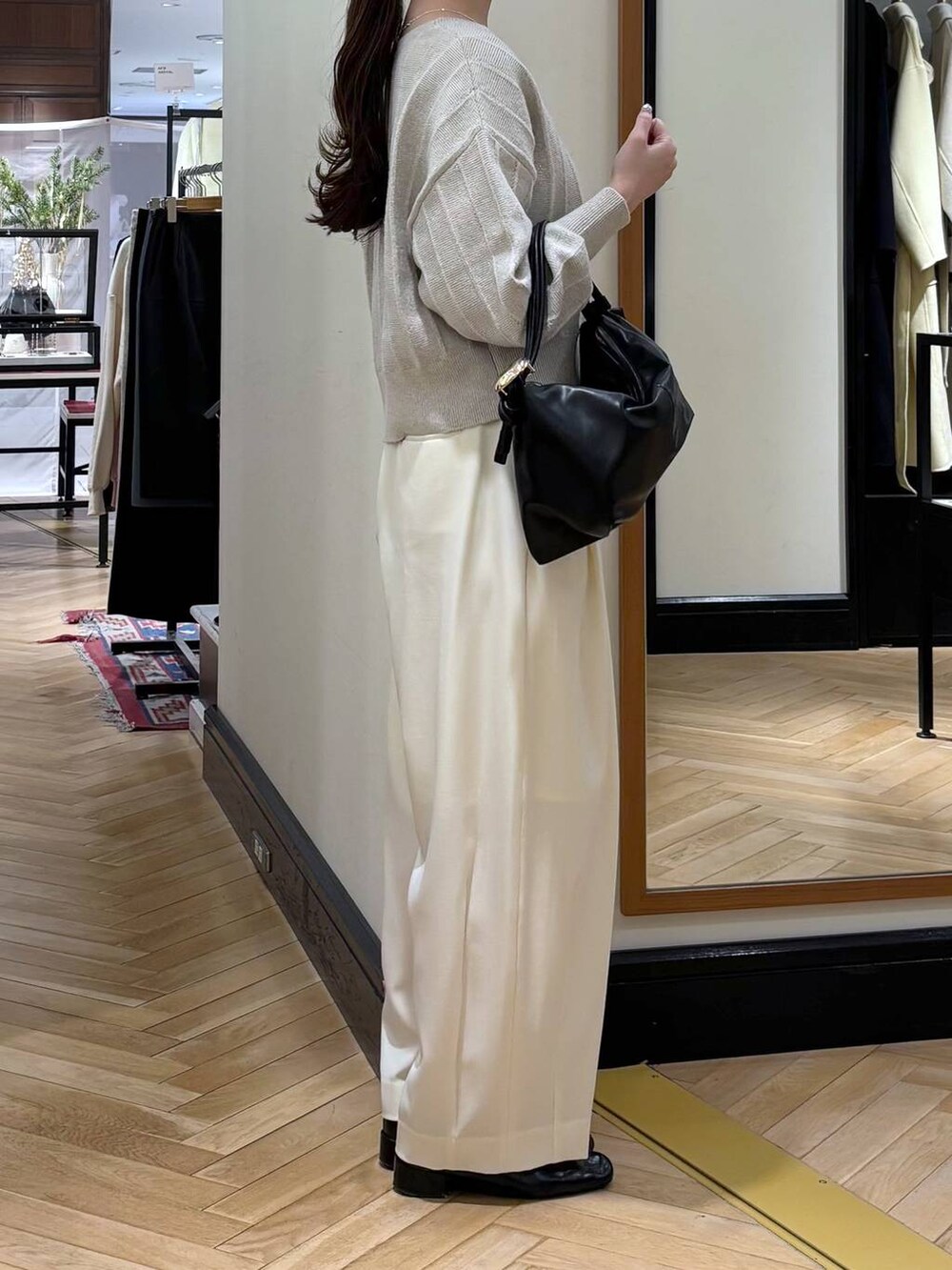 ホワイト系のスラックス、ブラック系のローファー、ブラック系のショルダーバッグを着用したレディースの冬コーディネートの2枚目の写真