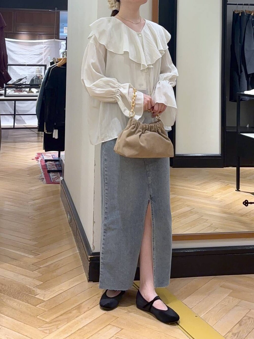 ブルー系のデニムスカート、ブラック系のバレエシューズ、ベージュ系のショルダーバッグを着用したレディースの秋コーディネートの2枚目の写真