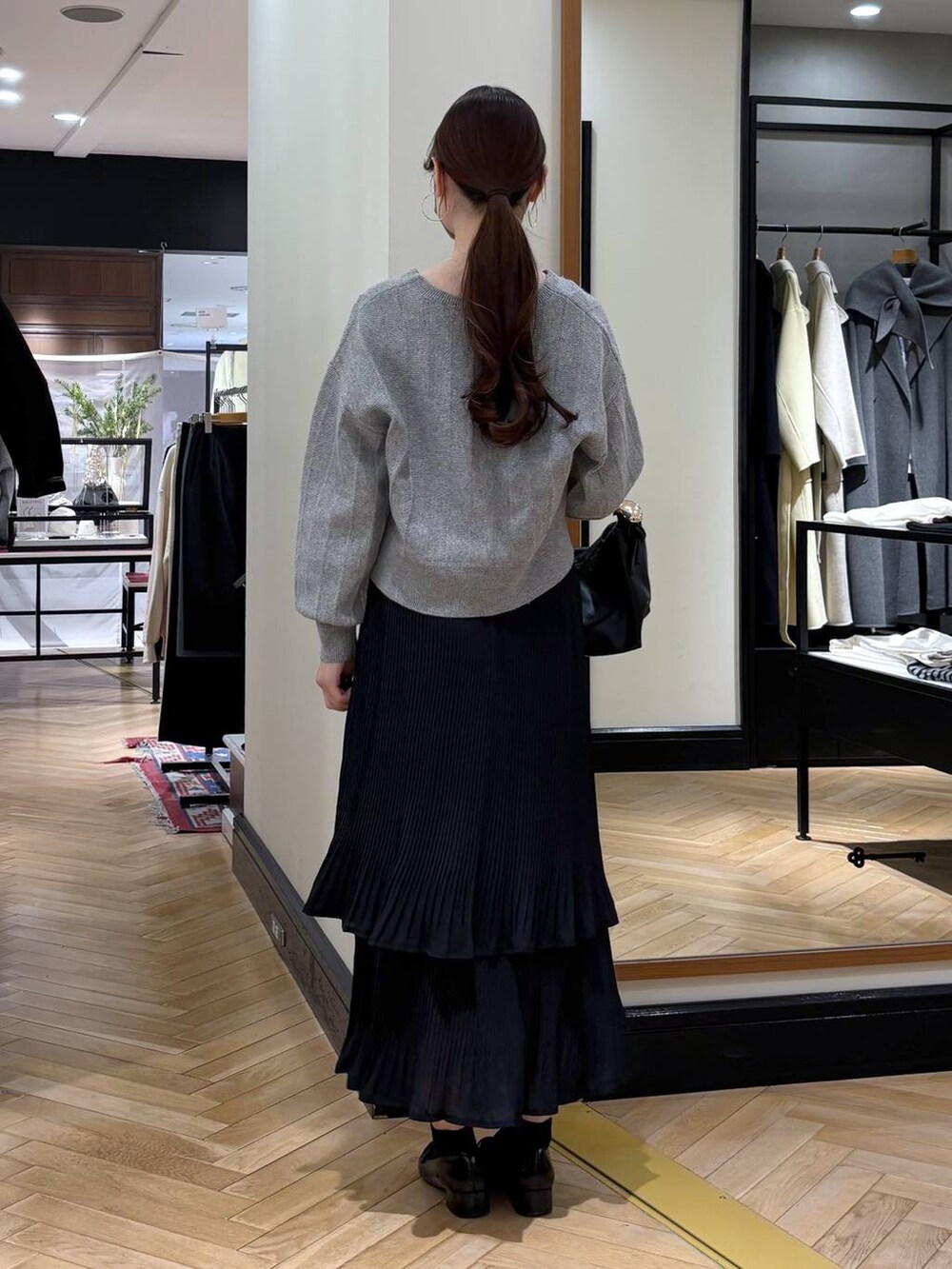 ブラック系のスカート、ブラック系のローファー、ブラック系のショルダーバッグを着用したレディースの冬コーディネートの4枚目の写真